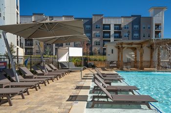 A pool area with sun loungers and a waterfall at The Delaney at East Park Apartments, Georgia, 30144